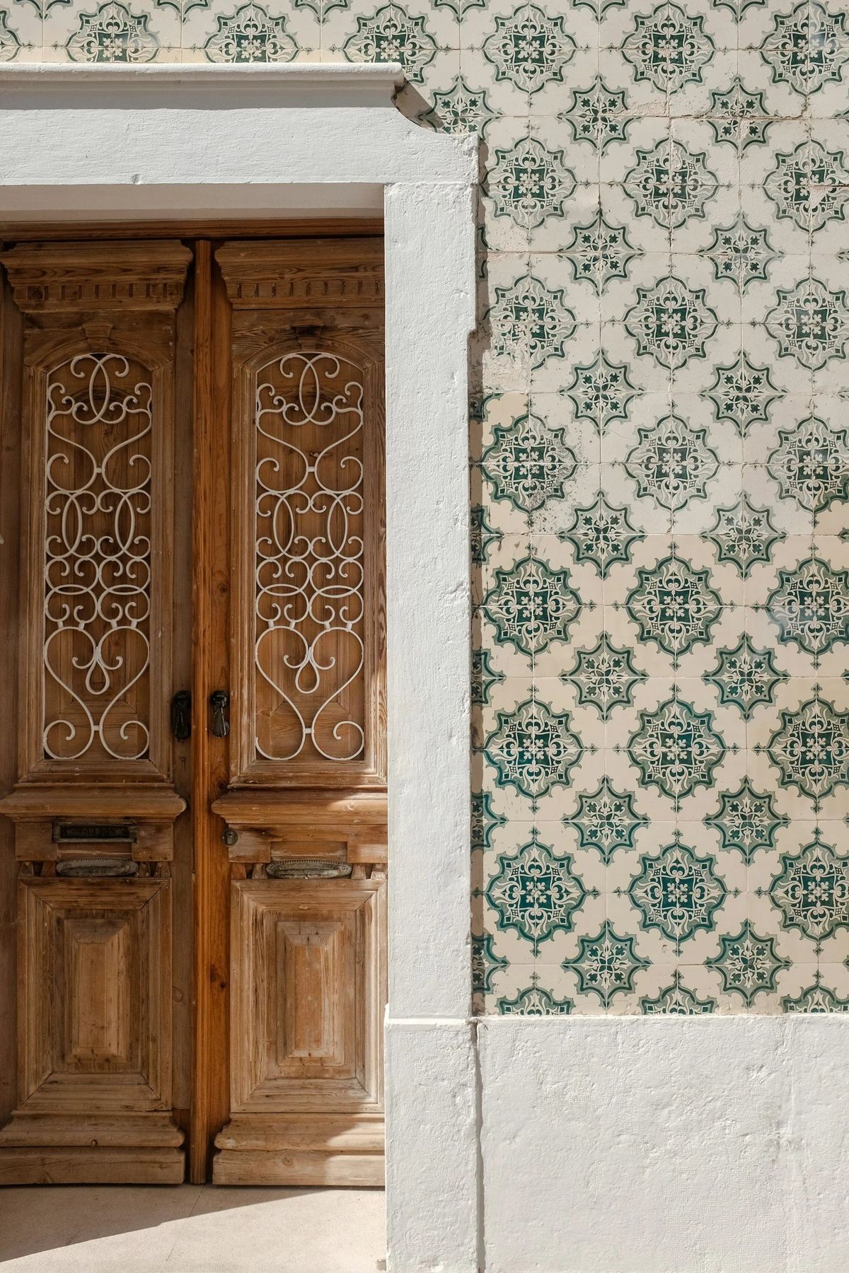 A carved wooden door beside a wall of Portuguese tiles