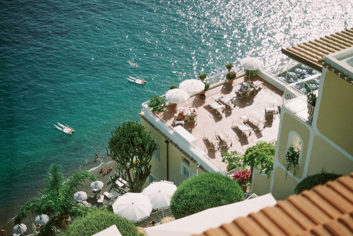 A hotel terrace with white parasols above a sparkling turquoise sea