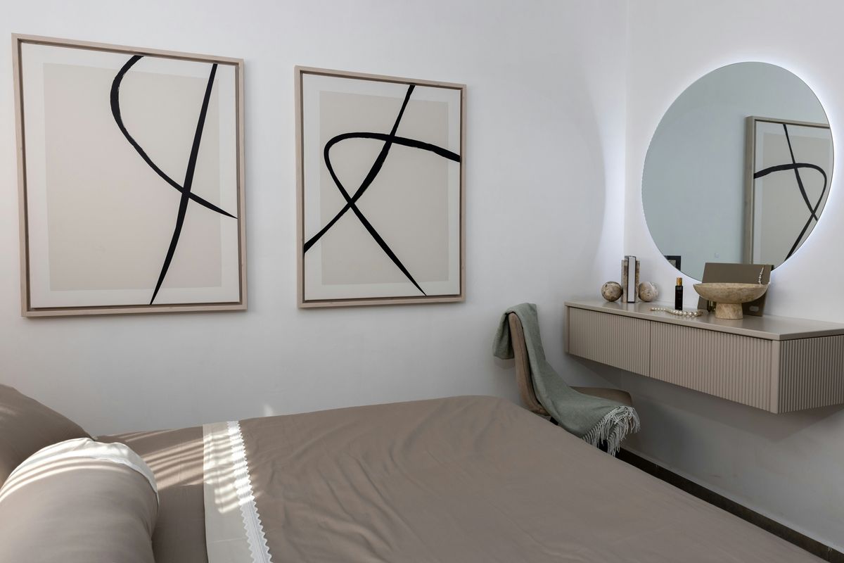 A minimalist bedroom with abstract art above a floating vanity
